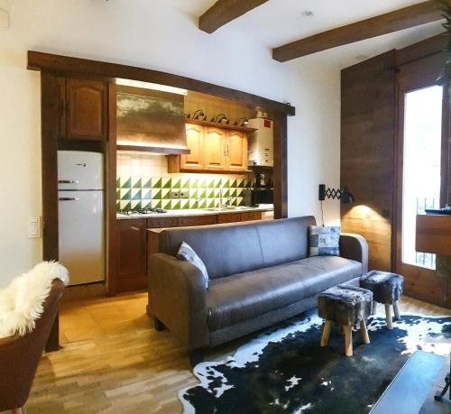 ein Wohnzimmer mit einem Sofa und einer Küche in der Unterkunft Casa Matilda - Apartamento con chimenea, vistas, rustico-elegante en el centro in Sant Joan de les Abadesses