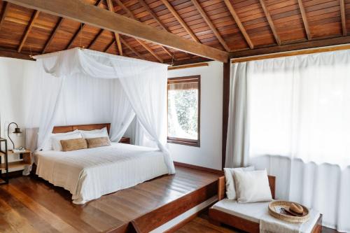 a bedroom with a canopy bed and a window at Vila Dos Orixás Boutique Hotel in Morro de São Paulo