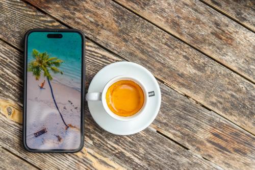 a cell phone and a cup of coffee on a table at Ari Grand Hotel & Spa in Dhangethi