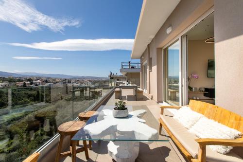 a balcony with a glass table and benches and a view at Gk Halepa Luxury apartment in Chania Town