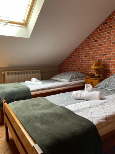 two beds in a room with a brick wall at Restauracja Rozmarzyn in Ostrzeszów