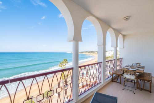 a balcony with a table and chairs and the beach at Frente ao Mar - Sea Front - 3 Quartos - wi-fi - Algarve in Armação de Pêra