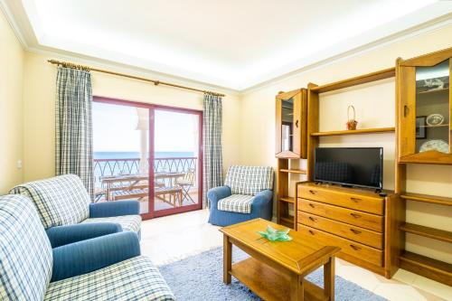 a living room with two blue chairs and a television at Frente ao Mar - Sea Front - 3 Quartos - wi-fi - Algarve in Armação de Pêra