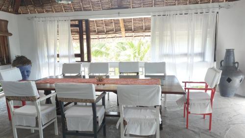 a dining room with a wooden table and white chairs at Waridi House in Watamu