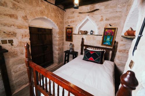 a bedroom with a wooden bed in a stone wall at نزل كوفان التراثي Koofan Heritage Lodge in Salalah