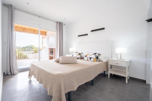 een witte slaapkamer met een groot bed en een raam bij Apartamento California Almadrava in Montjoys