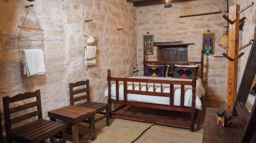 a bedroom with a wooden bed and two chairs at نزل كوفان التراثي Koofan Heritage Lodge in Salalah
