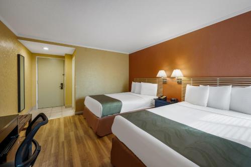 a hotel room with two beds and a television at Quality Inn JFK Airport Rockaway Blvd in Queens