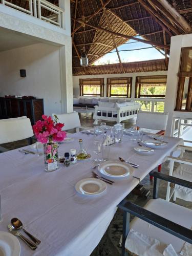 a long white table with plates and flowers on it at Waridi House in Watamu