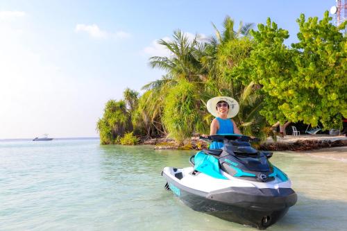 a boy is sitting on a jet ski in the water at Ari Grand Hotel & Spa in Dhangethi