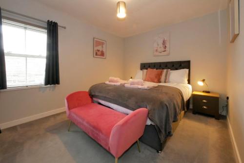 um quarto com uma cama e uma cadeira vermelha em Crewe Short Lets 2 Victoria Court, Crewe em Crewe