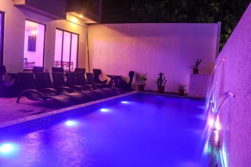 a swimming pool with a couch and chairs at night at Ari Grand Hotel & Spa in Dhangethi