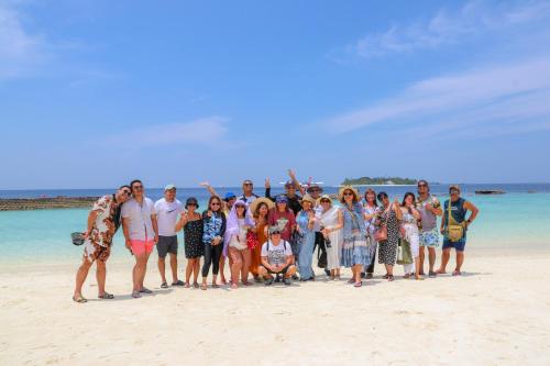 a group of people posing for a picture on the beach at Ari Grand Hotel & Spa in Dhangethi