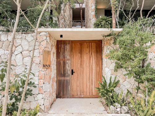 a wooden door on a stone building with trees at Teva Tulum, Aldea Zamá in Tulum