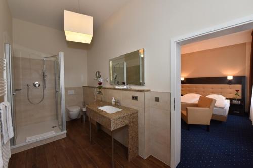 a bathroom with a sink and a shower and a bed at Weinhaus Wöhler in Schwerin