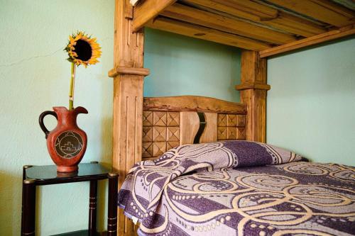 een slaapkamer met een houten bed en een vaas op een tafel bij Casa Hogareña y Artística in Carrillo