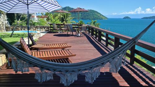 a hammock on a deck with a view of the ocean at Mirante da Figueira - Suítes para temporada in Angra dos Reis