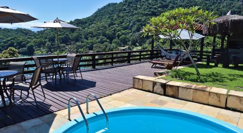 una terraza con piscina, mesas y sillas en Mirante da Figueira - Suítes para temporada, en Angra dos Reis
