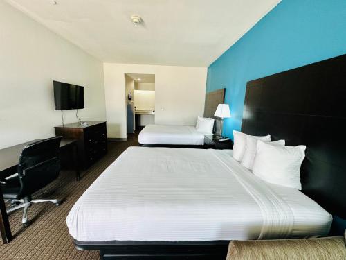 a hotel room with two beds and a desk and a tv at Lonestar Inn in El Campo