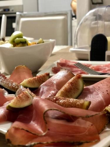 a plate of food with meat and fruit on a table at Montellinos Suite Tortora in SantʼAntìoco