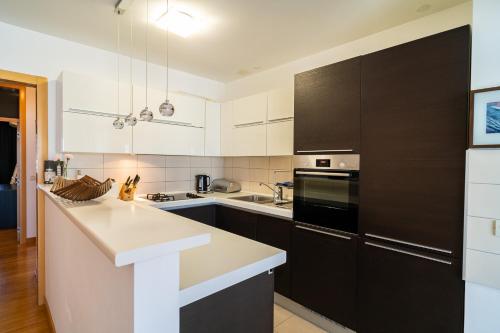 una cocina con armarios blancos y electrodomésticos negros en Apartment Cosmopolitan, en Zadar