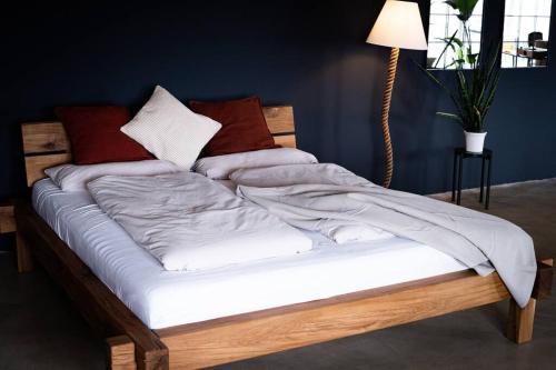 uma cama com lençóis brancos e almofadas em KiMMCo Loft em Schwetzingen