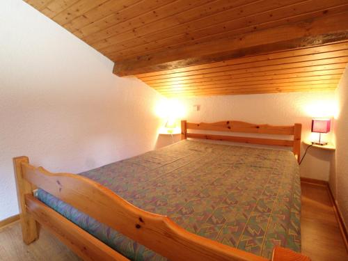 a wooden bed in a room with two lamps at Appartement Termignon, 3 pièces, 8 personnes - FR-1-508-79 in Termignon