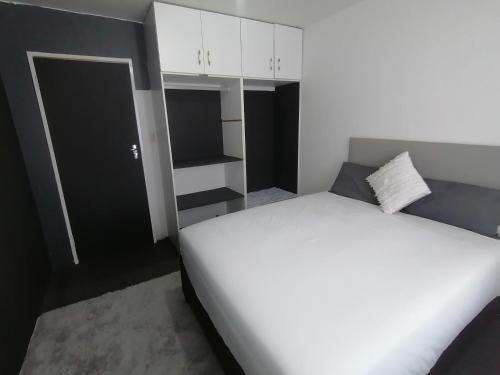 a bedroom with a large white bed and white cabinets at Budget Room in Pietermaritzburg