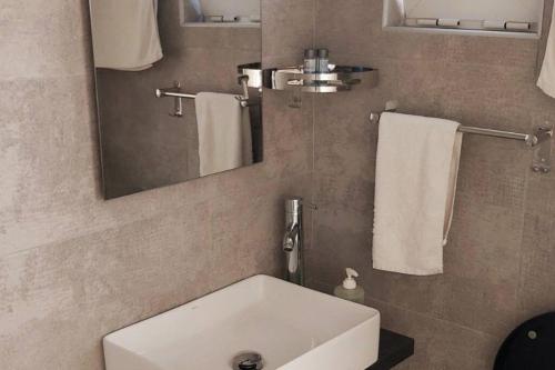 a bathroom with a sink and a mirror and towels at Quiet Studio with Athens View in Athens