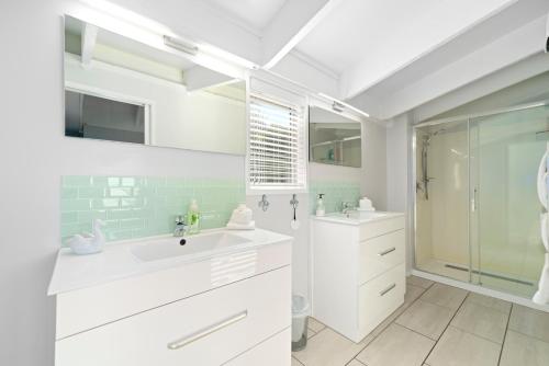 a white bathroom with a sink and a shower at Botanical HideAway Taupo in Taupo