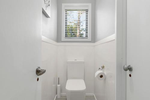 タウポにあるBotanical HideAway Taupoのトイレと窓のある白いバスルーム