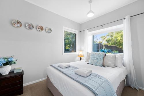 a white bedroom with a bed and a window at Botanical HideAway Taupo in Taupo