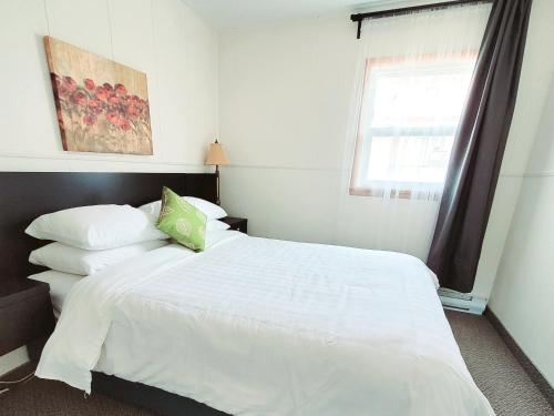 sypialnia z łóżkiem z białą pościelą i oknem w obiekcie Lido Motel w mieście Radium Hot Springs