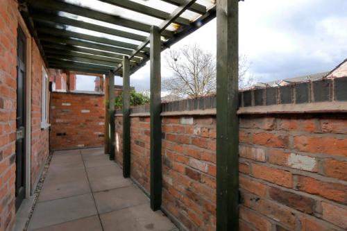 a brick wall with a pergola on it at Crewe Short Lets 6 Victoria Court, Crewe in Crewe