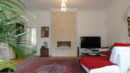 a living room with a white couch and a tv at The Old Rectory Apartment in Milton Keynes