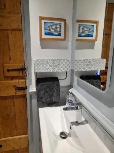 uma casa de banho com um lavatório branco e um espelho. em Pinetree Cottage, dog friendly, Holiday let, Callander Invertrossachs em Callander