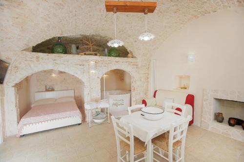 1 dormitorio con mesa, cama, mesa y sillas en Dimora Alfieri, en Cisternino