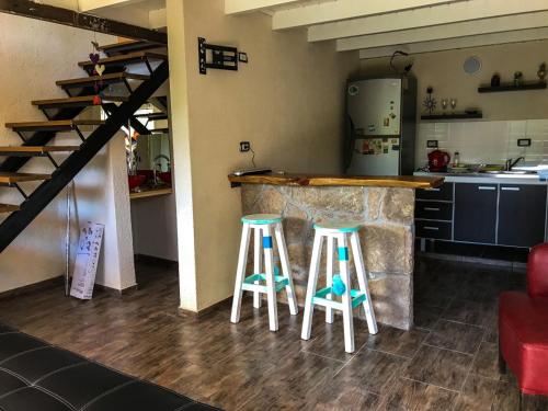 a kitchen with two bar stools next to a counter at Departamentos El Milagro in Tanti