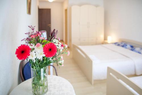 a vase filled with red and white flowers on a table at Sun Guest House in Budva