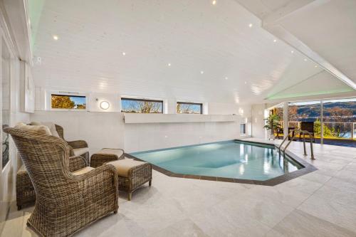 a living room with a swimming pool and chairs at Villa Arboretet - Seaside villa with private pool & infrared sauna in the heart of Arboretet, Bergen in Bergen