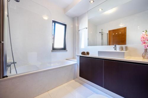 a bathroom with a tub and a sink and a bath tub at Baia da Luz - Tropicana Beach Apartment in Luz