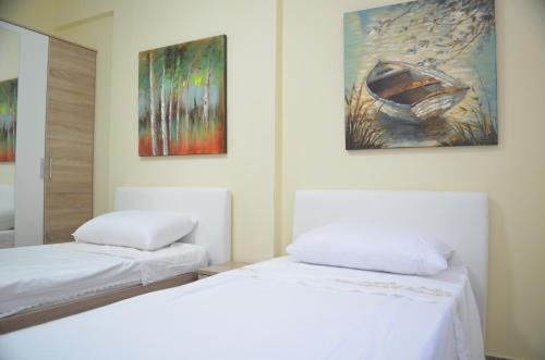 duas camas num quarto com pinturas na parede em Home Sweet Home by the Sea - 060 em Durrës