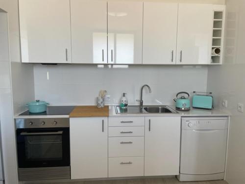 uma cozinha com armários brancos, um lavatório e uma máquina de lavar louça em Pópulo Mar em Ponta Delgada