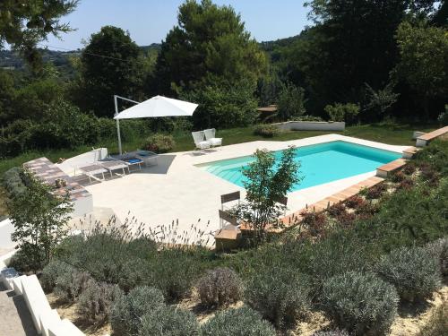 a pool in a yard with chairs and an umbrella at Casa Sant Angelo in Pesaro