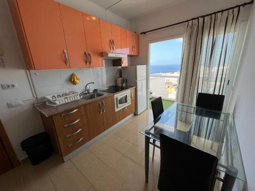 een kleine keuken met een glazen tafel, een tafel en een raam bij ALCAMAR Habitaciones con baño compartido en apartamentos rurales cerca al Mar! in Alcalá