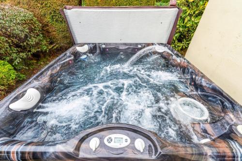 a hot tub with water in it in the grass at Pass the Keys Malt House With Hot Tub Stunning Tudor Cottage in Craven Arms