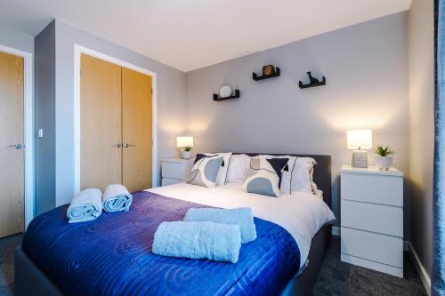 ein Schlafzimmer mit einem großen Bett mit zwei Handtüchern darauf in der Unterkunft MODERN 2 BEDROOM 2 BATHROOM APARTMENT SLEEPS 4 IN WARRINGTON FOR WORK AND LEISURE WITH PRIVATE PARKING BY AMAZING SPACES RELOCATIONS Ltd in Warrington