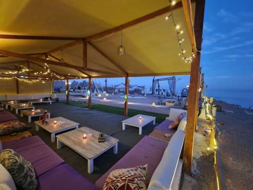 a tent with couches and tables and a view of the ocean at Dahab Hills Villa and Studios in Dahab