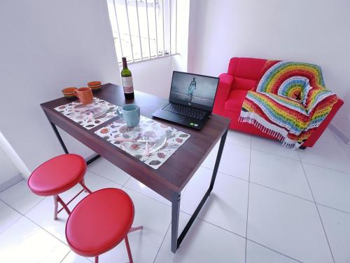 una camera con tavolo, computer portatile e divano rosso di São Francisco Aparts a Salvador