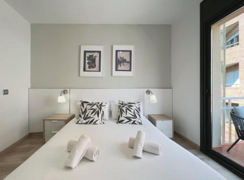 a white bedroom with a large white bed with three pillows at Stay U-nique Apartments Sant Eudald in Barcelona